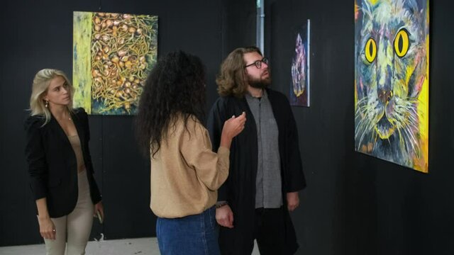 group of art lovers are visiting modern museum, viewing pictures