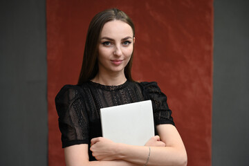 Business concept young brunette girl holding a folder in her hands on a maroon background