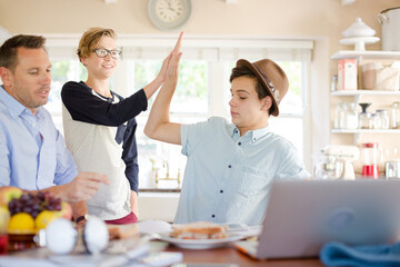 Mid adult man watching teenage boys doing high five