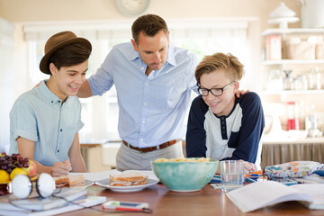 Teenage boys with father using laptop in dining room