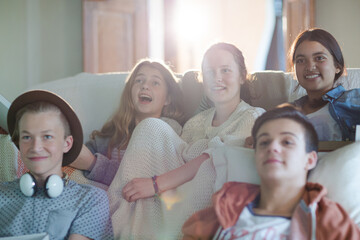 Group of teenagers watching tv on sofa together