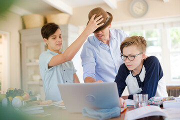 Obraz premium Teenage boys with father using laptop in dining room