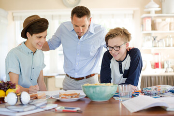 Obraz na płótnie Canvas Teenage boys with father using laptop in dining room
