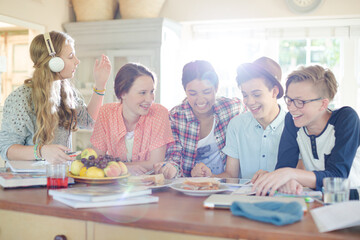 Group of smiling teenagers gathered around table in dining room