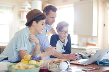 Obraz na płótnie Canvas Teenage boys with father using laptop in dining room