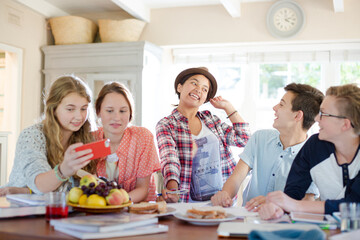 Group of smiling teenagers gathered around table in dining room
