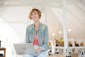 Portrait of woman sitting at desk with laptop in office