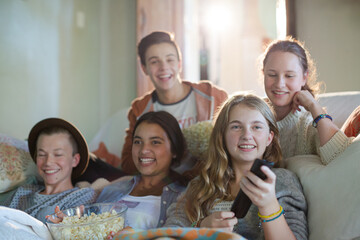 Group of teenagers having fun while watching tv on sofa