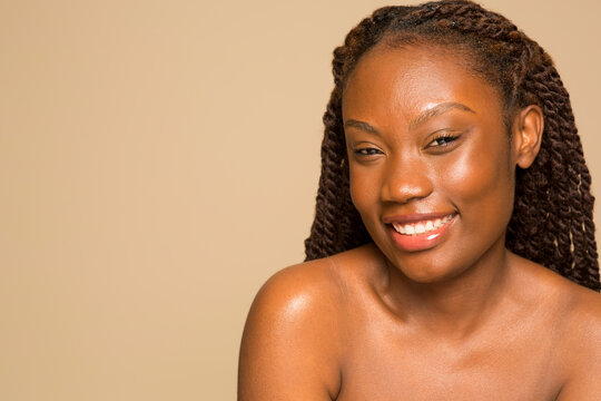 Studio portrait of smiling shirtless woman with braided hair