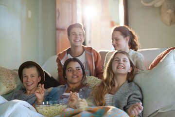 Group of teenagers having fun while watching tv on sofa