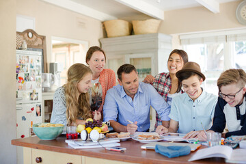 Teenagers with mid adult man sitting at table in dining room