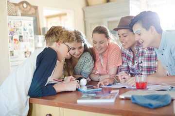 Fototapeta premium Group of teenagers using together digital tablet at table in kitchen