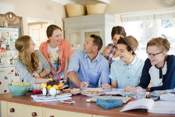 Fototapeta premium Teenagers with mid adult man sitting at table in dining room