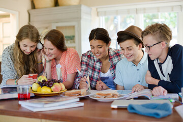 Group of smiling teenagers gathered around table in dining room