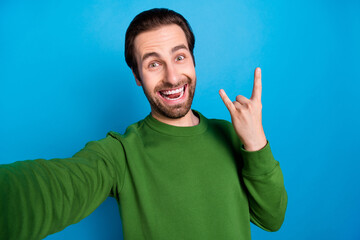 Photo of young excited crazy smiling brutal guy take selfie show rock'n'roll sign careless isolated on blue color background