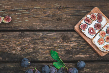 Cream cheese sandwich with figs served on wooden board with copy space