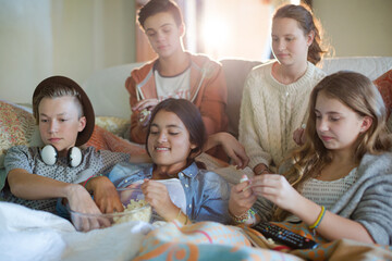 Group of teenagers throwing popcorn on themselves while sitting on sofa