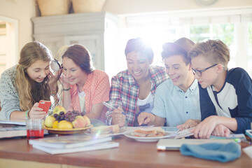 Group of smiling teenagers gathered around table in dining room