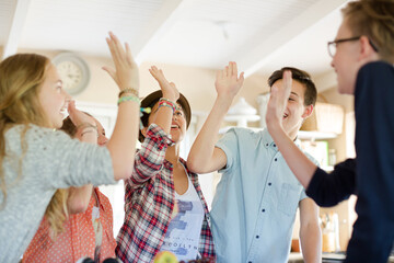 Group of teenagers doing high five in living room