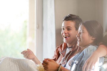 Teenage couple lying in bed and throwing popcorn