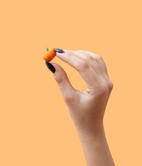 Halloween minimalist creative concept of hand holds miniature pumpkin. Copy space. 