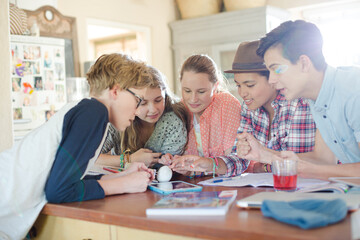 Group of teenagers using together digital tablet at table in kitchen