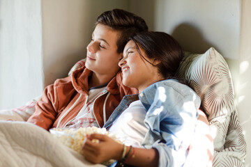 Teenage couple lying in bed and watching tv