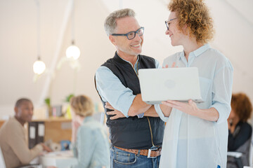 Fototapeta premium Portrait of man and woman with laptop, smiling in office