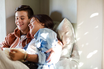 Teenage couple lying in bed and watching tv