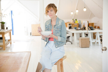 Portrait of woman sitting on desk  in office