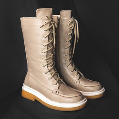 Light brown wellington boots on a black background. Women shoes close-up