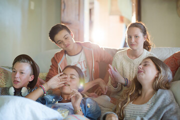 Group of teenagers throwing popcorn on themselves while sitting on sofa
