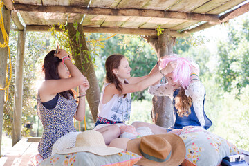 Obraz na płótnie Canvas Three teenage girls wearing wigs hat while sitting in tree house in summer