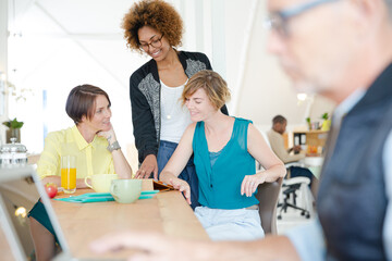 Women looking at digital tablet and smiling in office