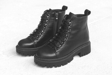 Black stylish footwear. Women boots on a concrete background. Female modern and casual style concept