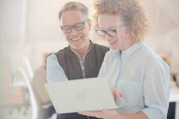 Portrait of man and woman with laptop, smiling in office