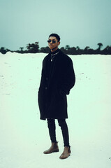 Portrait of stylish man standing on sand