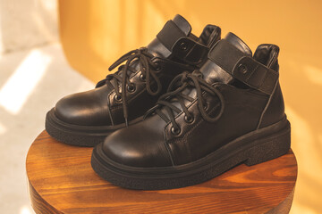 Black women boots. Female autumn and winter footwear on a wooden stand. Modern design photo