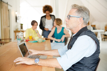 Fototapeta premium Portrait of man using laptop , woman laughing in background