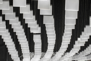 Row of contemporary hanging square LED lighting in modern building with high black ceiling