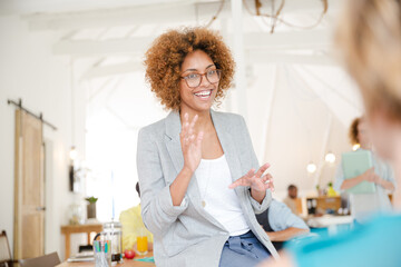 Portrait of young woman sitting at desk and talking