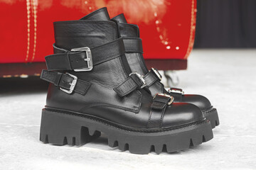Black women boots with clasps, close-up view. Studio photo on concrete background