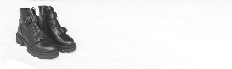 Woman black footwear banner. Black leather boots on white concrete background with copy space