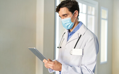 Doctor with face mask reads email or patient file