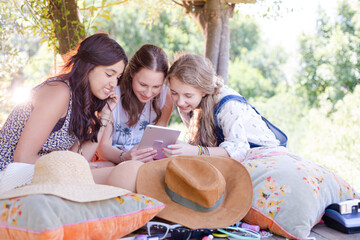 Fototapeta premium Three teenage girls using digital tablet in tree house