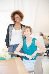 Women using digital tablet and smiling in office