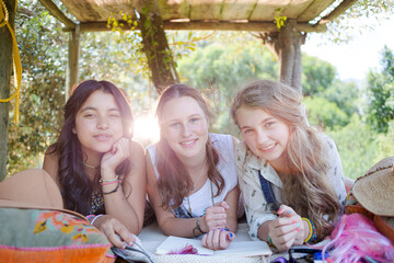 Three teenage girls reading magazine while lying in tree house in summer