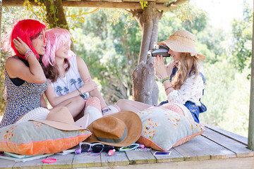 Three teenage girls wearing wigs hat while sitting in tree house in summer