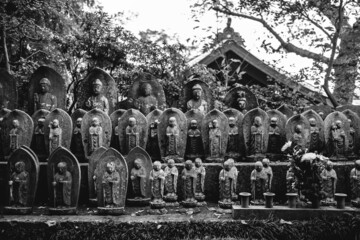 Lots of beautiful and very old little buddhist stone statues and carvings in garden of a buddhist temple, Kamakura, Japan (in black and white)