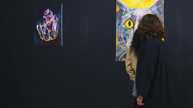 man and woman are looking on pictures in contemporary abstract style in gallery